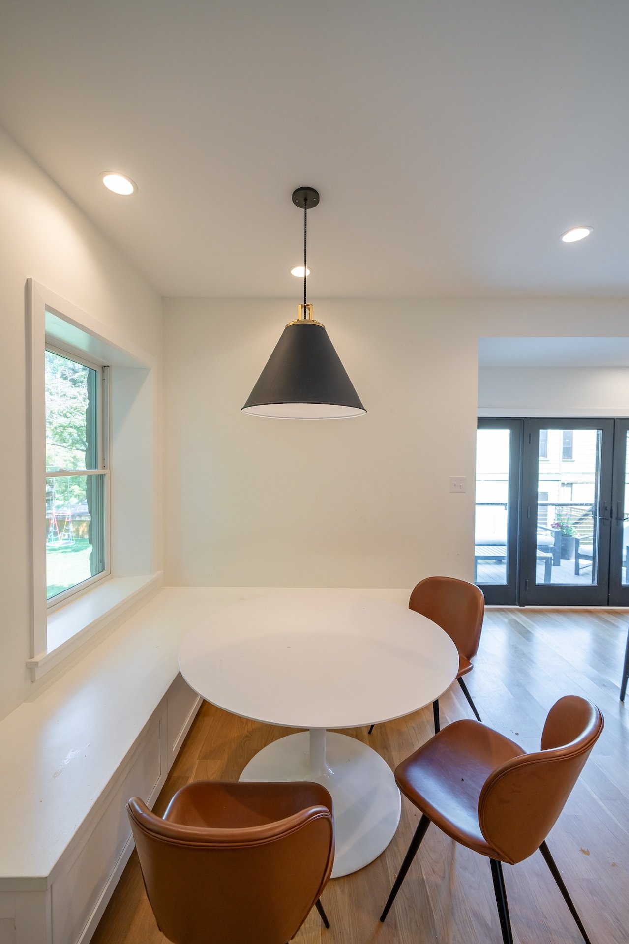 Small modern dining area with brown leather chairs and white table