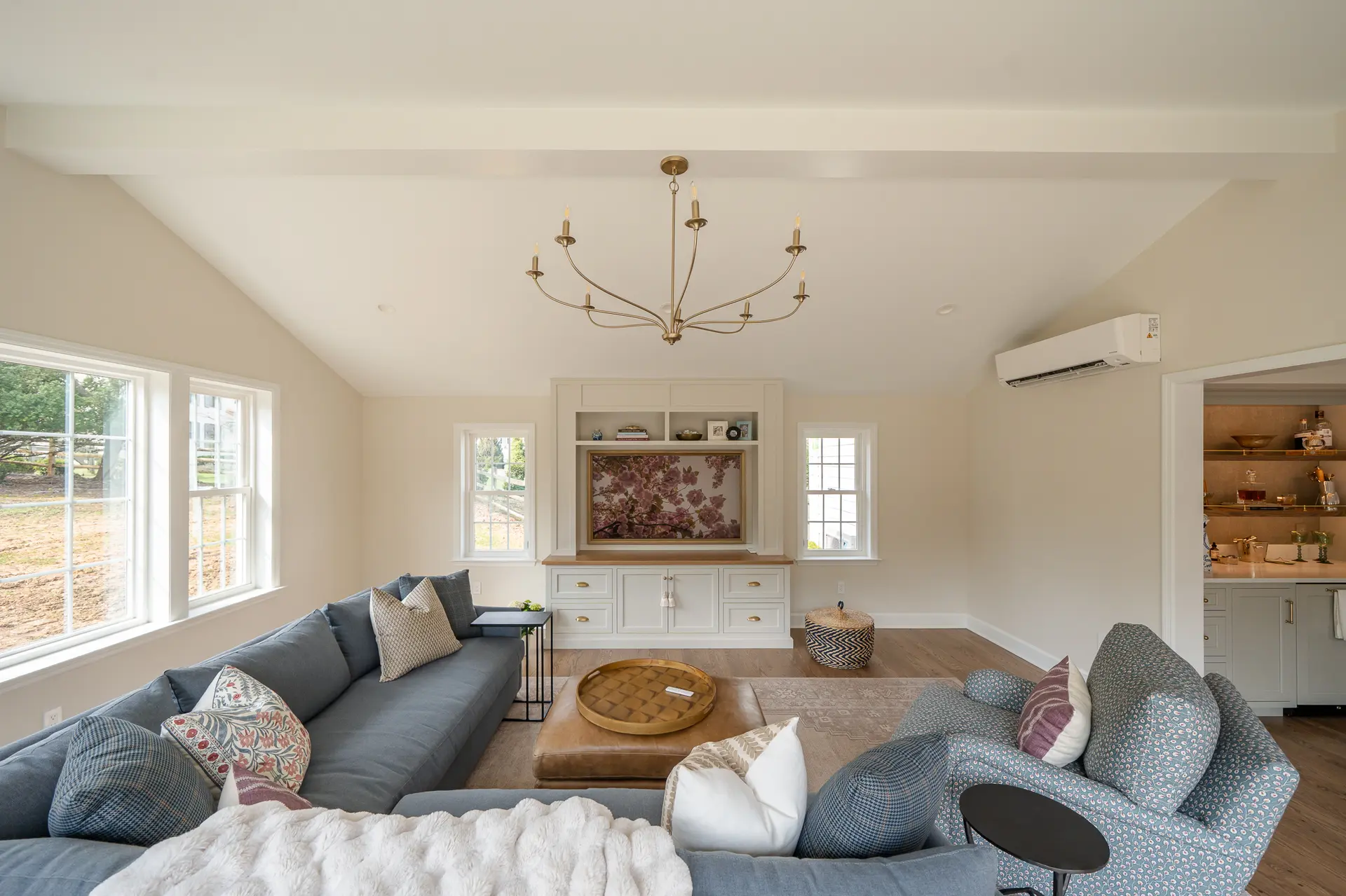 Bright great room with custom entertainment center and view into dining area with dry bar