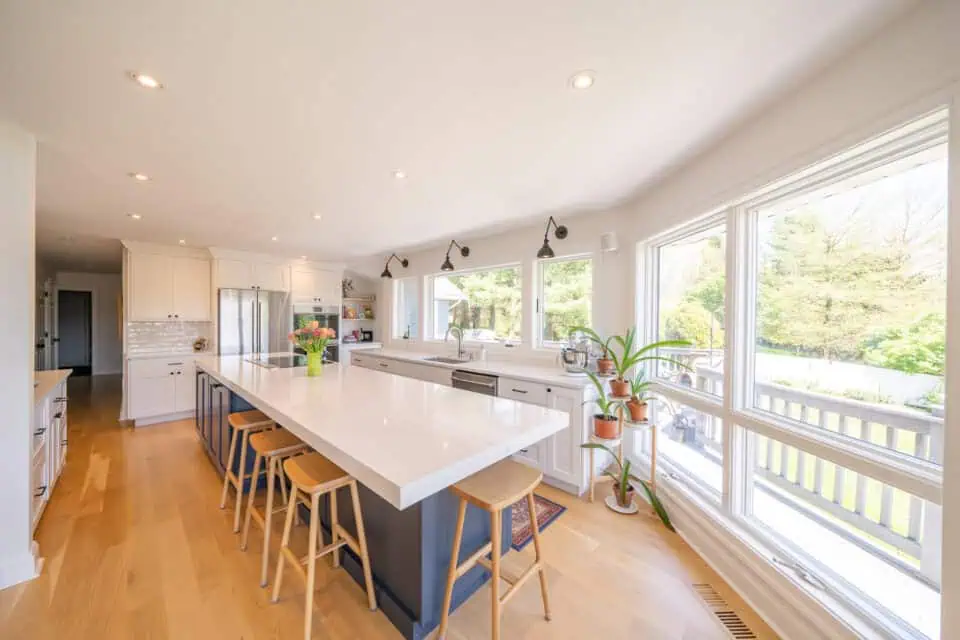 Sun-filled kitchen with large island surrounded by wooden stools