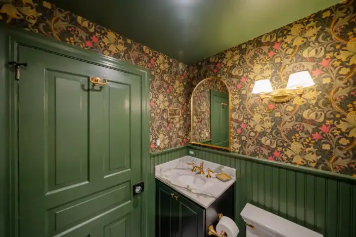 Unique deep-color themed bathroom with a green painted door and gold wallpaper