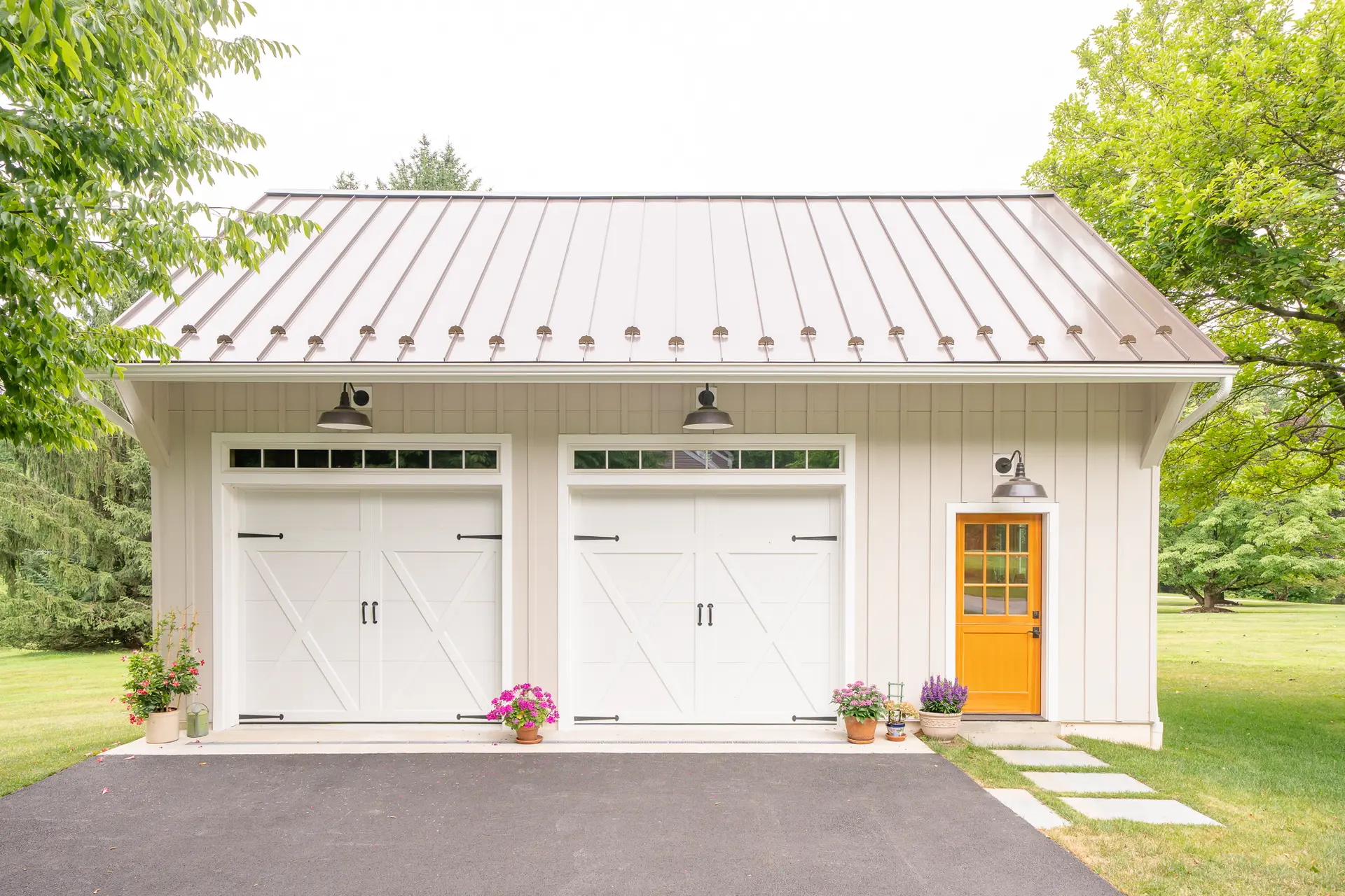 Detached two-bay garage addition in Thornton, PA with white board-and-batten siding and an orange Dutch door