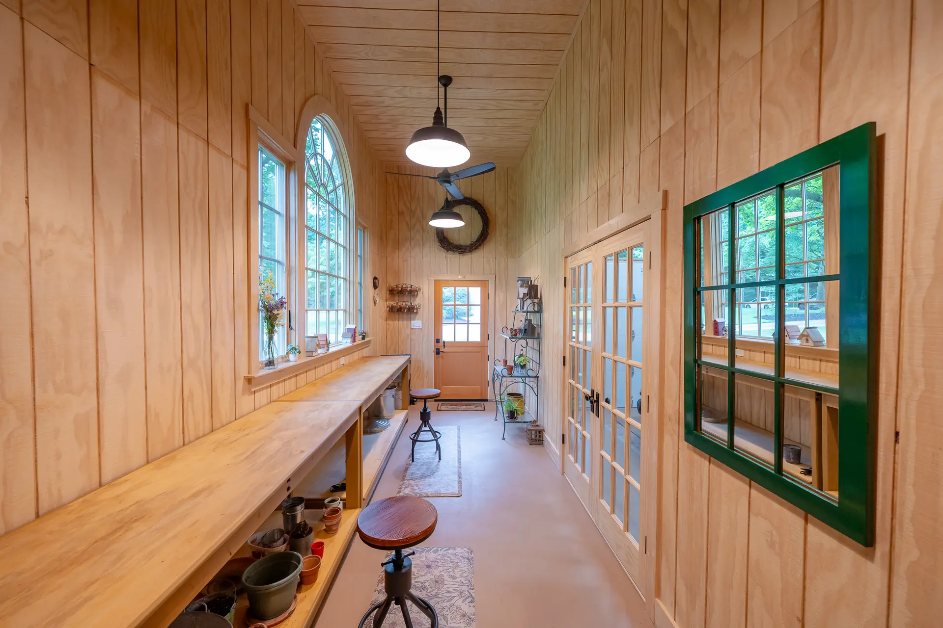 Potting shed workspace hallway with a built-in wood bench, arched window, and French doors to the garage