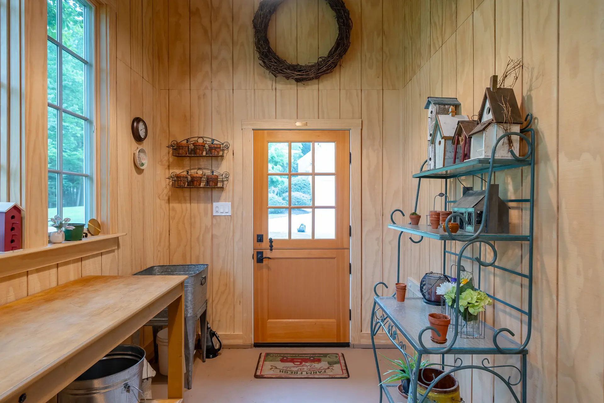 Potting shed interior with a grapevine wreath, birdhouses, and a vintage-style bakers rack