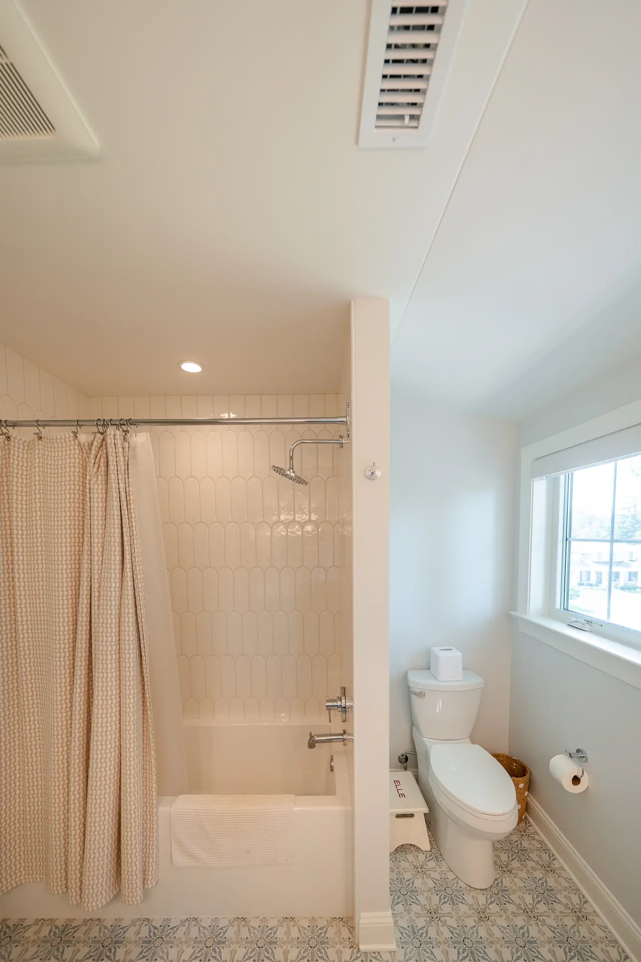 Primary bathroom double vanity with arched brass mirrors and green cabinetry