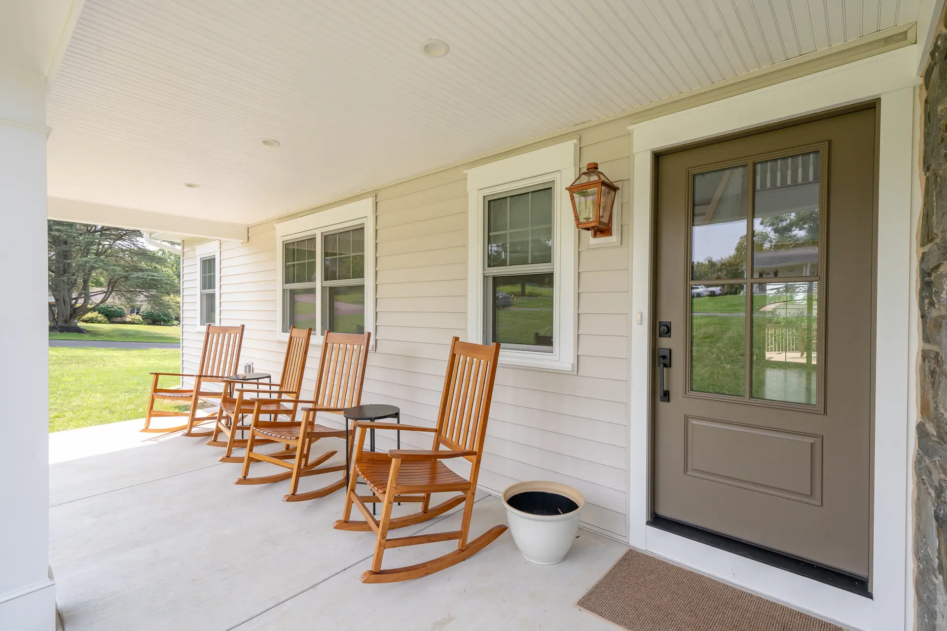 Front porch of the West Chester renovation with wooden rocking chairs and a new entry door