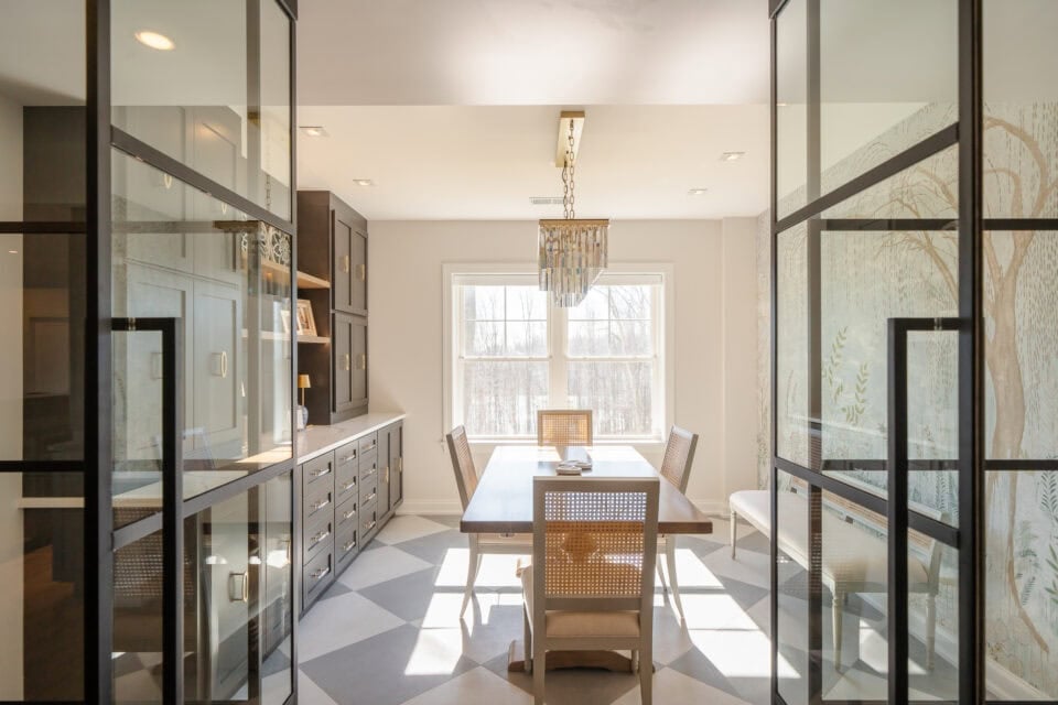Glass doors with black metal frames opening to a formal dining room