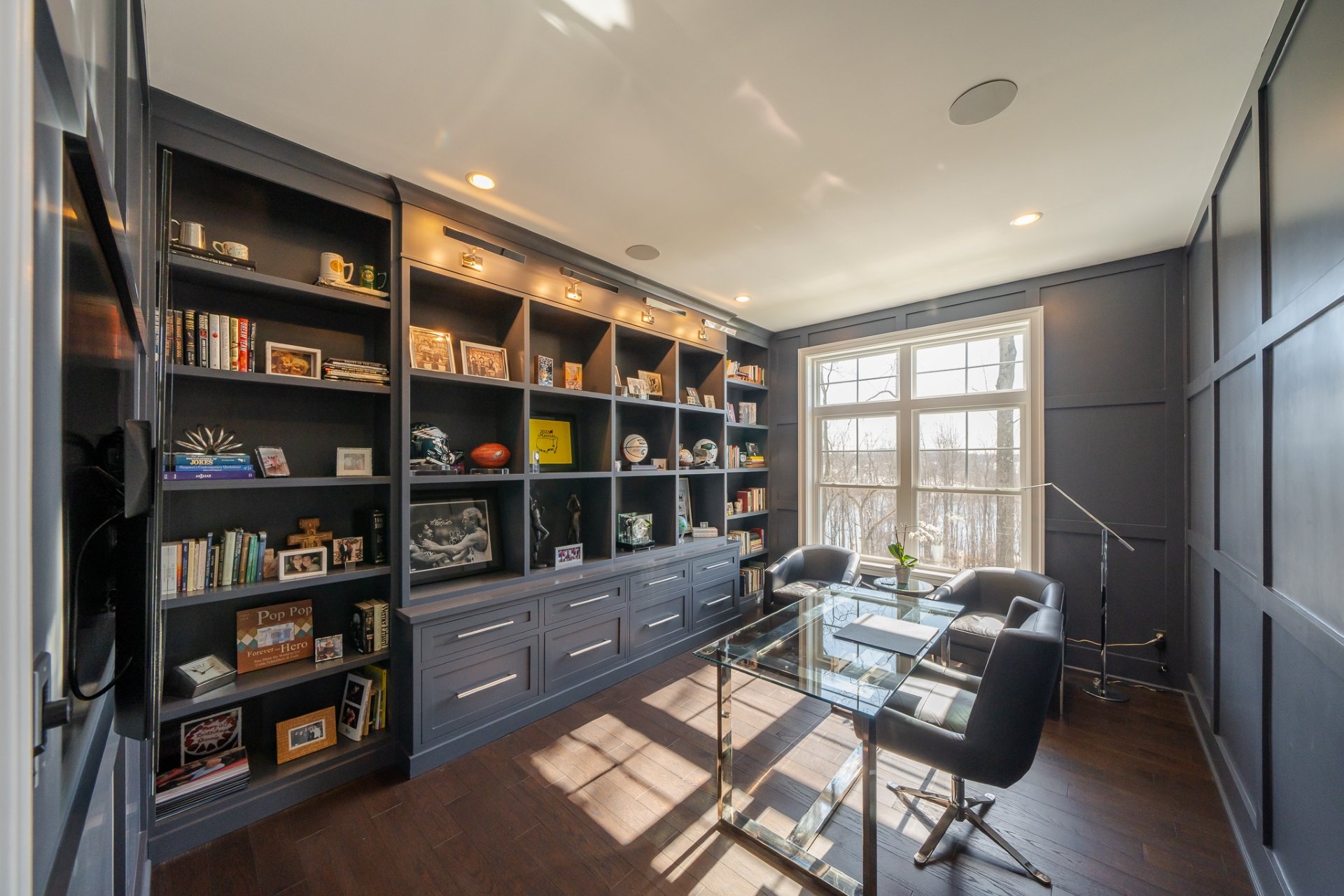 Home office with grey built-in shelves and glass desk