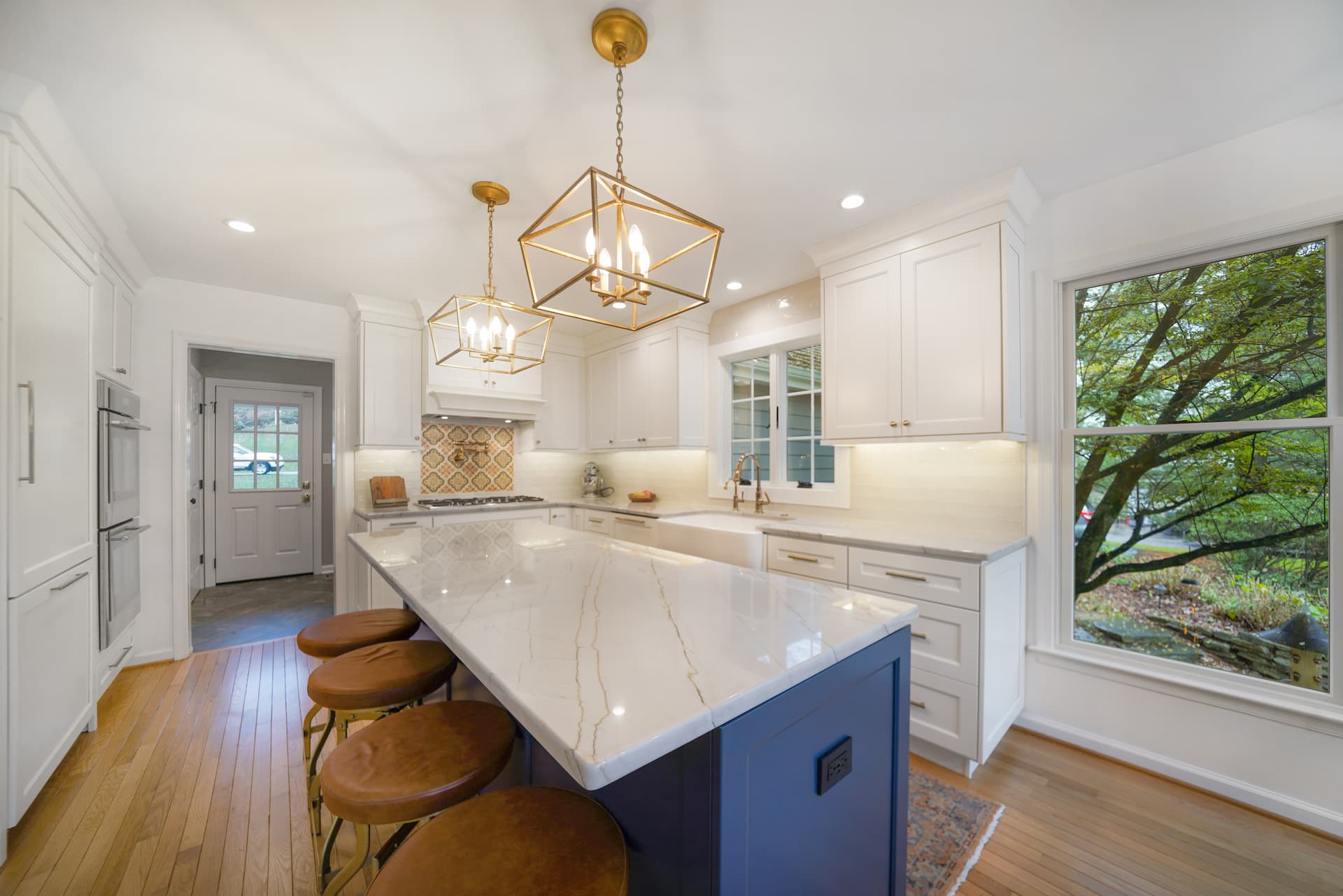 Remodeled white kitchen with brass drawer pulls and blue island