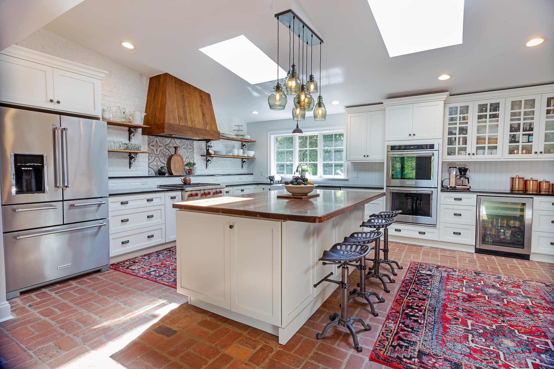 Light-filled renovated kitchen with white cabinets and a decorative range hood