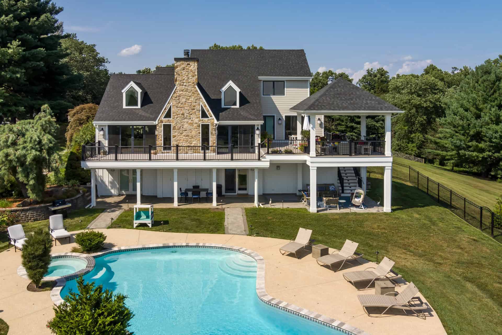 Back of home with wraparound deck and kidney-shaped pool